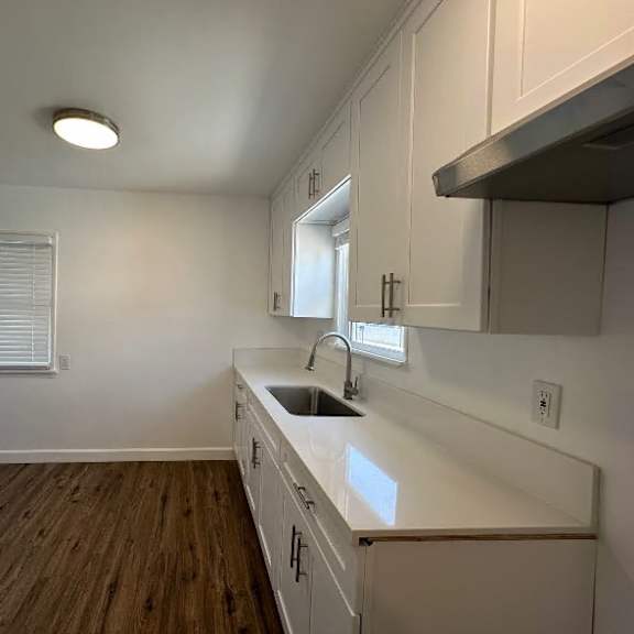 a kitchen with white cabinets and a wooden floor.