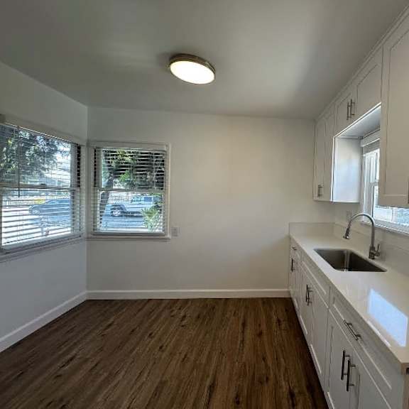 a kitchen with white cabinets and a wooden floor.