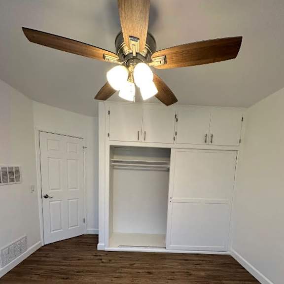 a room with a ceiling fan and wooden floors.