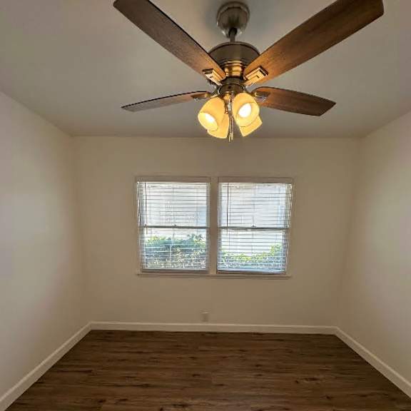 a room with a ceiling fan and wooden flooring.