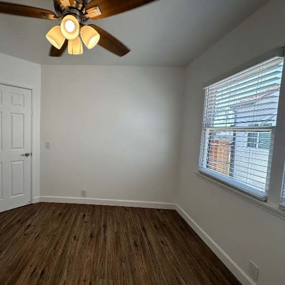 a room with a ceiling fan and wooden flooring.