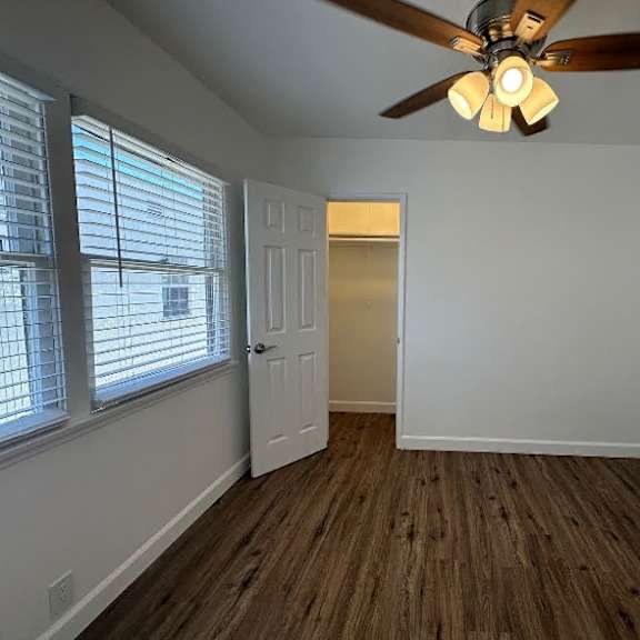 a room with a ceiling fan and wooden flooring.