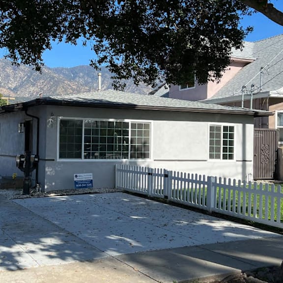 a white house with a grey roof and a white picket fence.