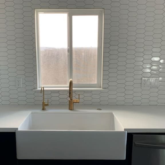 a white sink with gold faucets in a modern kitchen.