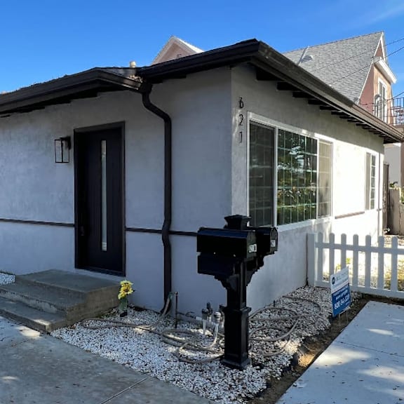 a small house with a black door and a mailbox on the side.