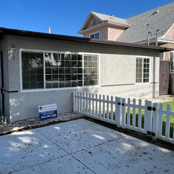 a small house with a white picket fence and a sign on the front.