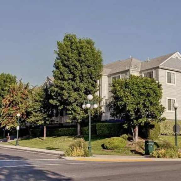 a large house with a grey roof and white walls is surrounded by trees and bushes.