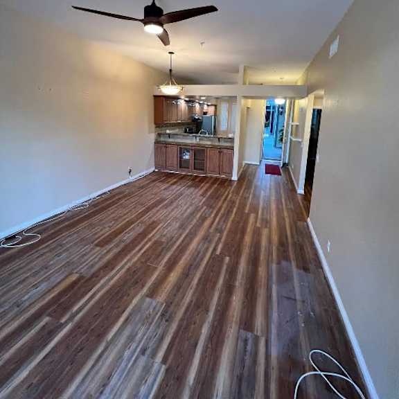 a room with a ceiling fan and wooden flooring.
