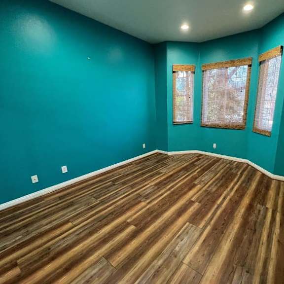 a room with wooden flooring and two windows.
