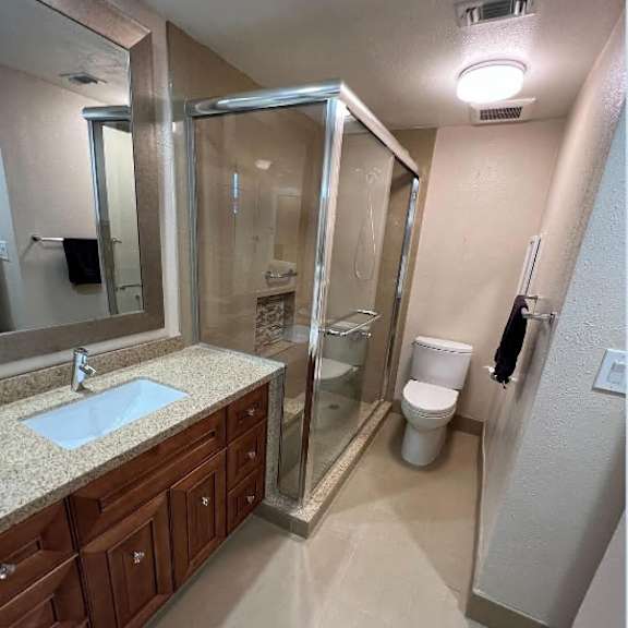 a bathroom with a sink, toilet, and shower.