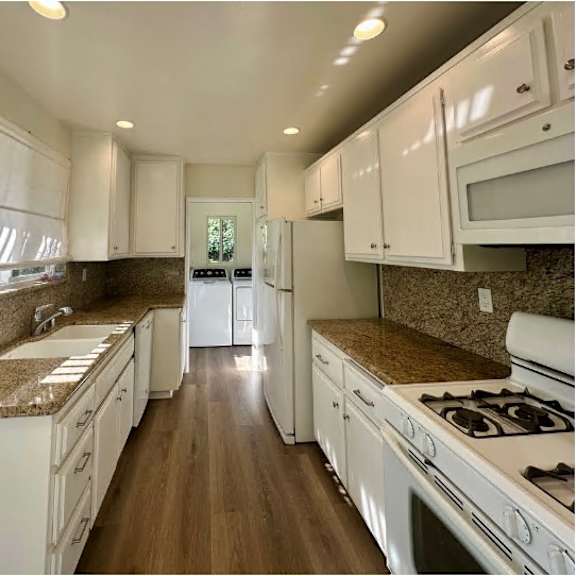 a kitchen with white cabinets and a granite countertop.