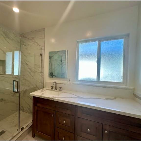 a bathroom with a marble shower and a window.