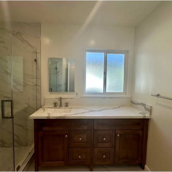 a bathroom with a marble shower and a vanity with a mirror.