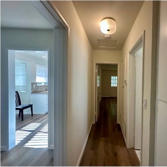 a long hallway with white doors and a bench.