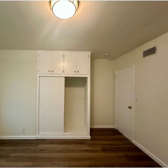 a room with a white cabinet and a window with blinds.