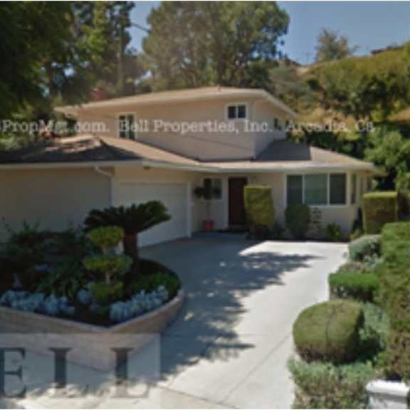a house with a driveway and bushes in front.