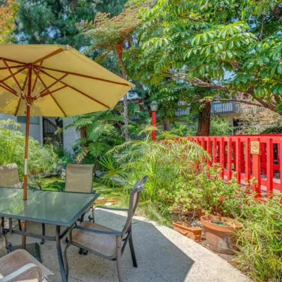 a table with chairs and an umbrella is set up in a garden.