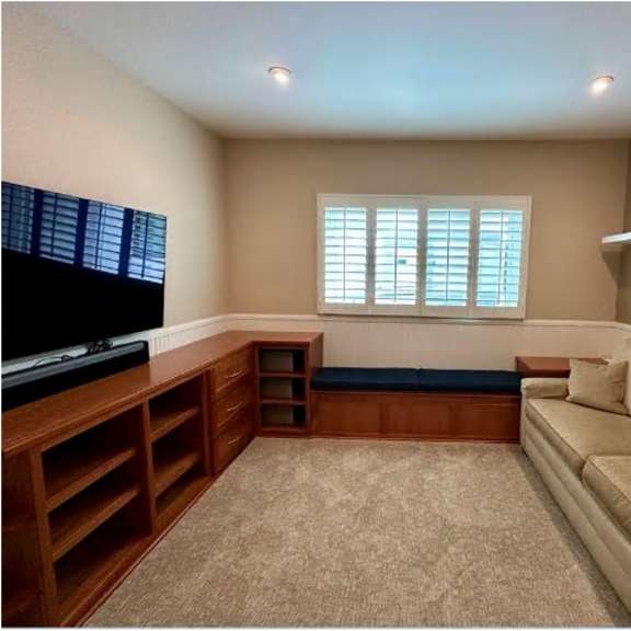 a living room with a couch, a television, and a window with blinds.