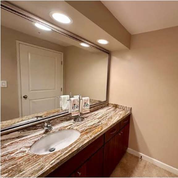 a bathroom with a marble countertop and a large mirror.