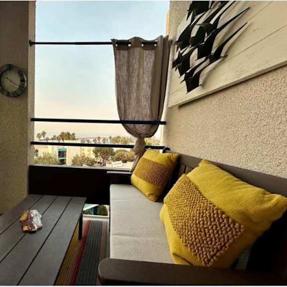 a balcony with a bench, pillows, and a clock on the wall.