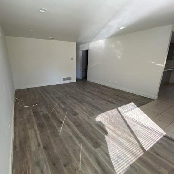 a room with wooden flooring and white walls is shown.