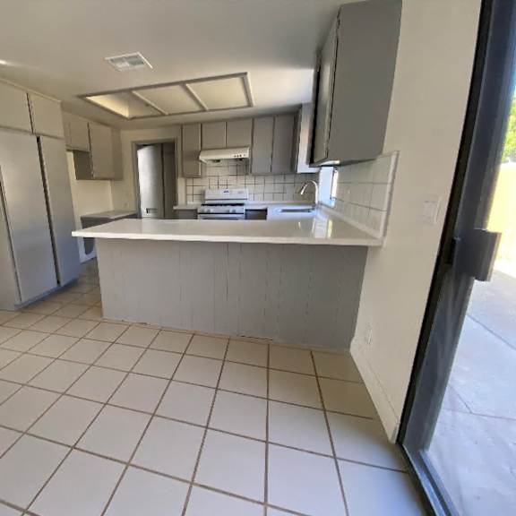 a kitchen with white tiles and stainless steel appliances.