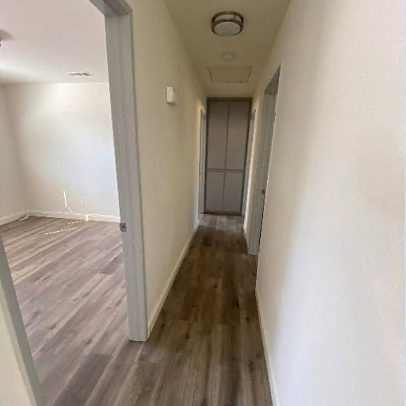 a long hallway with wood flooring and white walls.