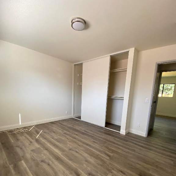 a room with a light switch on the wall and a wooden floor.