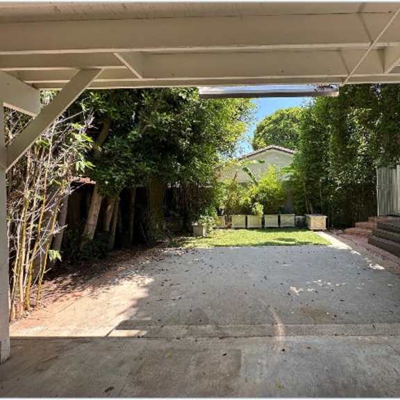 a driveway leads to a house with a white porch.
