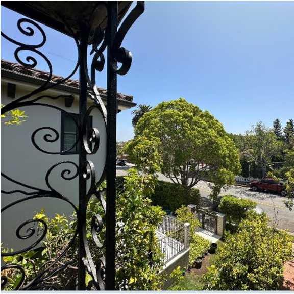 a view from a balcony looking out at a tree and a car.