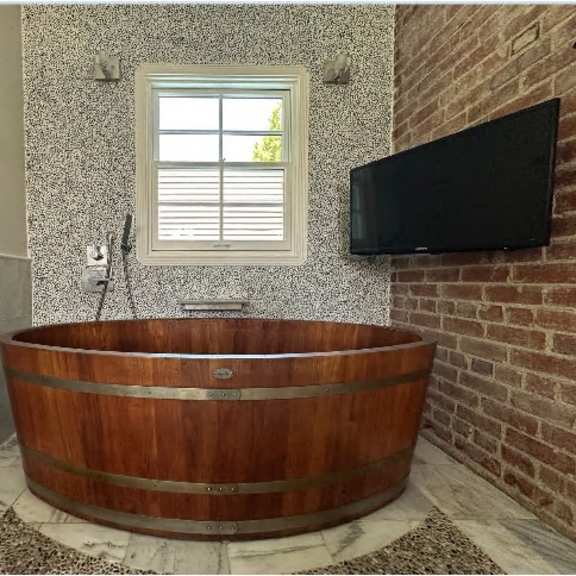 a wooden tub sits in a bathroom with a window above it.