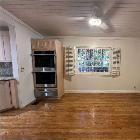 a kitchen with a stove top oven and a fan on the ceiling.