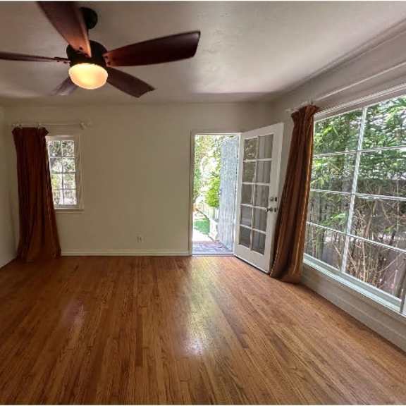 a room with a ceiling fan and wooden flooring.