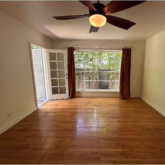 a room with a ceiling fan and sliding glass doors.