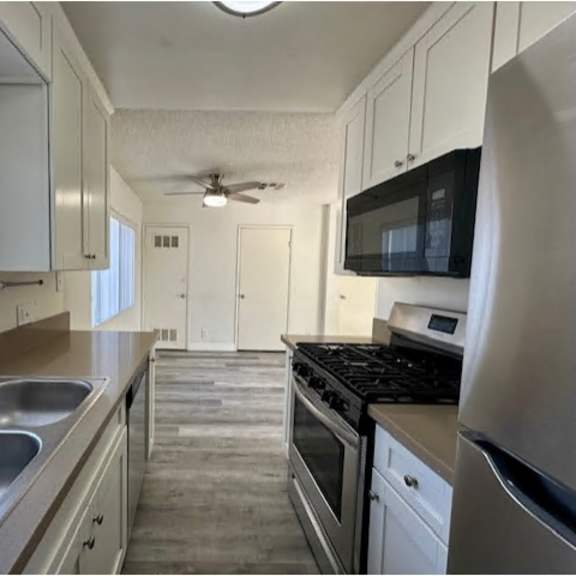 a kitchen with white cabinets and stainless steel appliances.