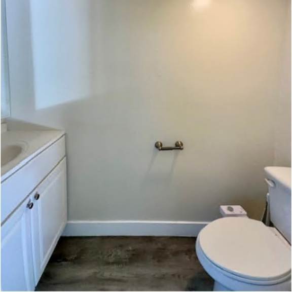 a white toilet sits in a bathroom with a white sink and a white cabinet.
