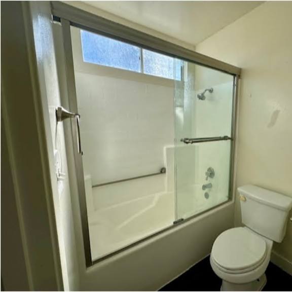 a white toilet sits next to a glass shower door in a bathroom.