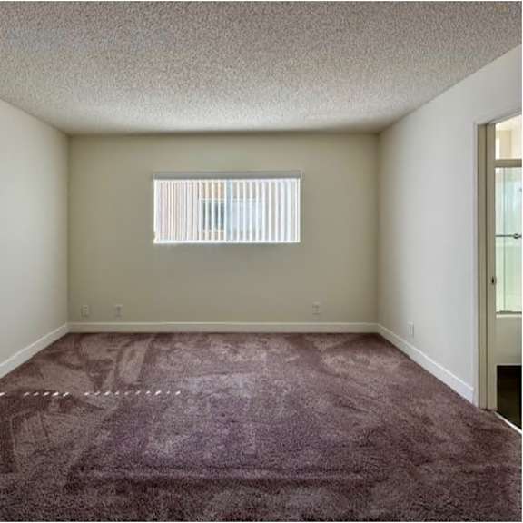 a room with a carpeted floor and a window with blinds.
