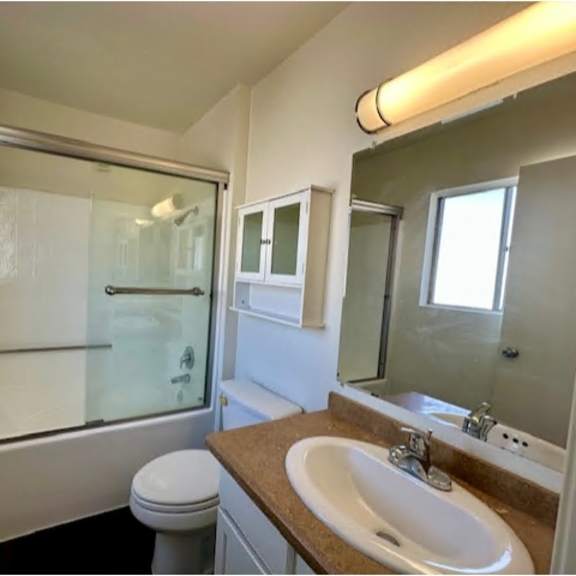 a bathroom with a toilet, sink, and shower.