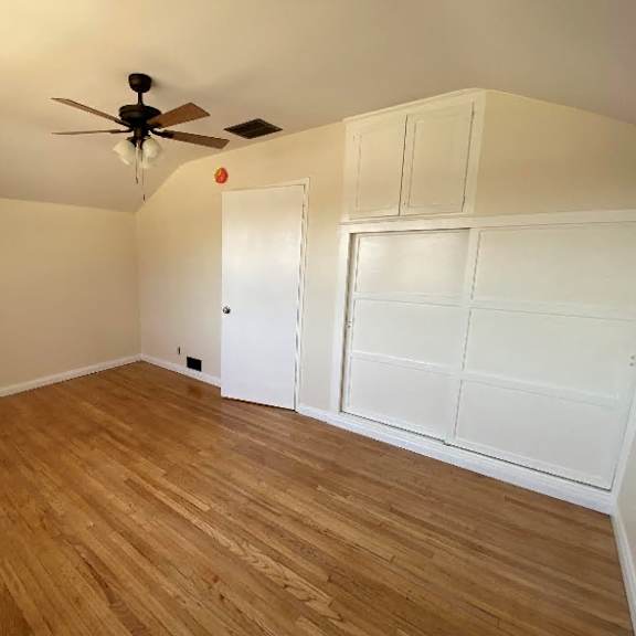 a room with a ceiling fan and wooden flooring.