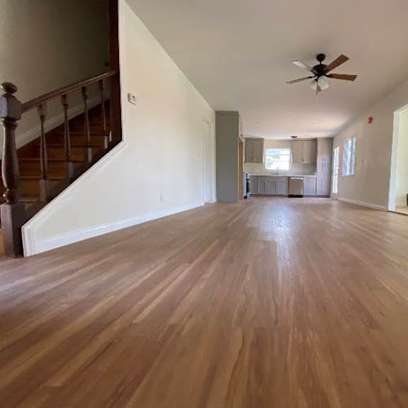 a spacious room with wooden flooring and a ceiling fan.