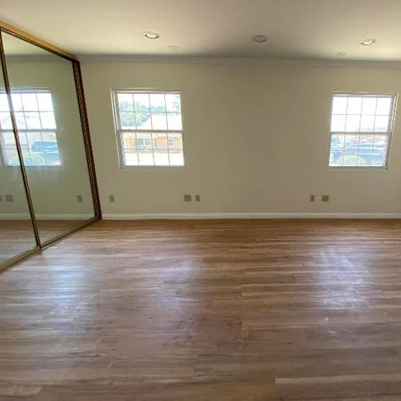 a room with wooden flooring and two windows.