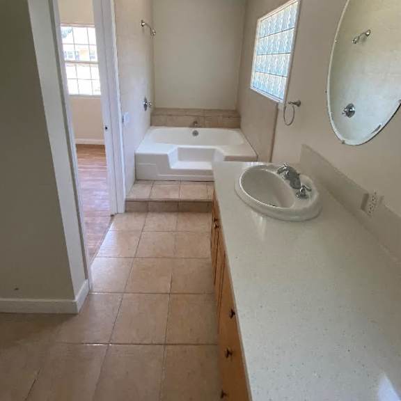 a bathroom with a sink, mirror, and bathtub.