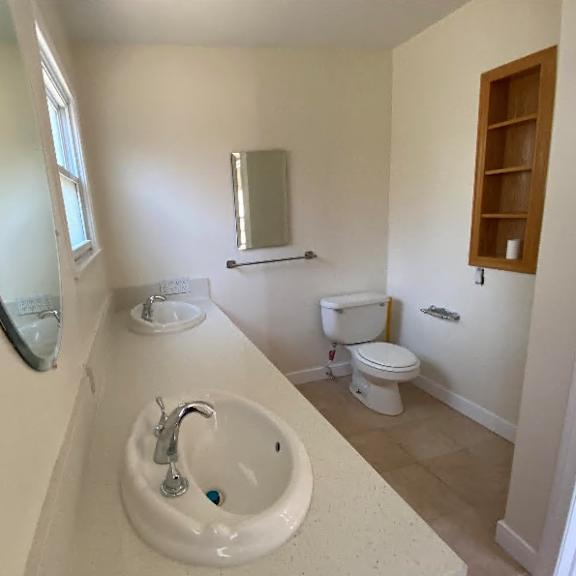 a bathroom with a sink, toilet, and mirror.
