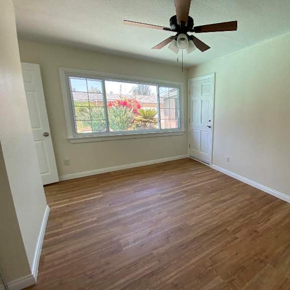 a room with a ceiling fan and wooden flooring.