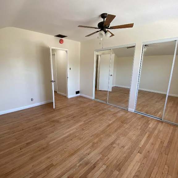 a room with wooden floors and a ceiling fan.