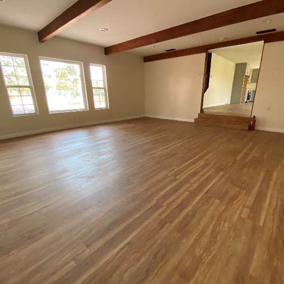 a room with wooden flooring and a large mirror on the wall.