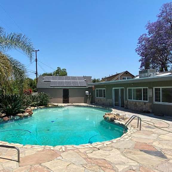 a small pool surrounded by a stone patio and a metal ladder.