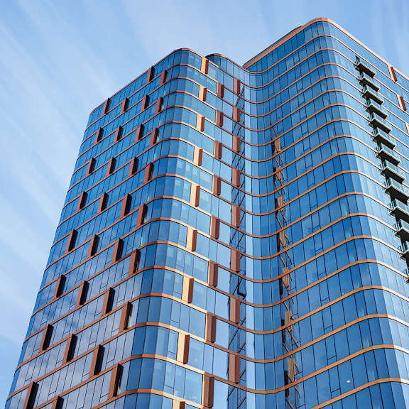 a tall building with blue glass windows and orange trim.