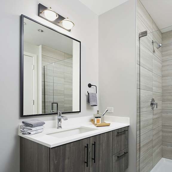 a bathroom with a sink, mirror, and shower.